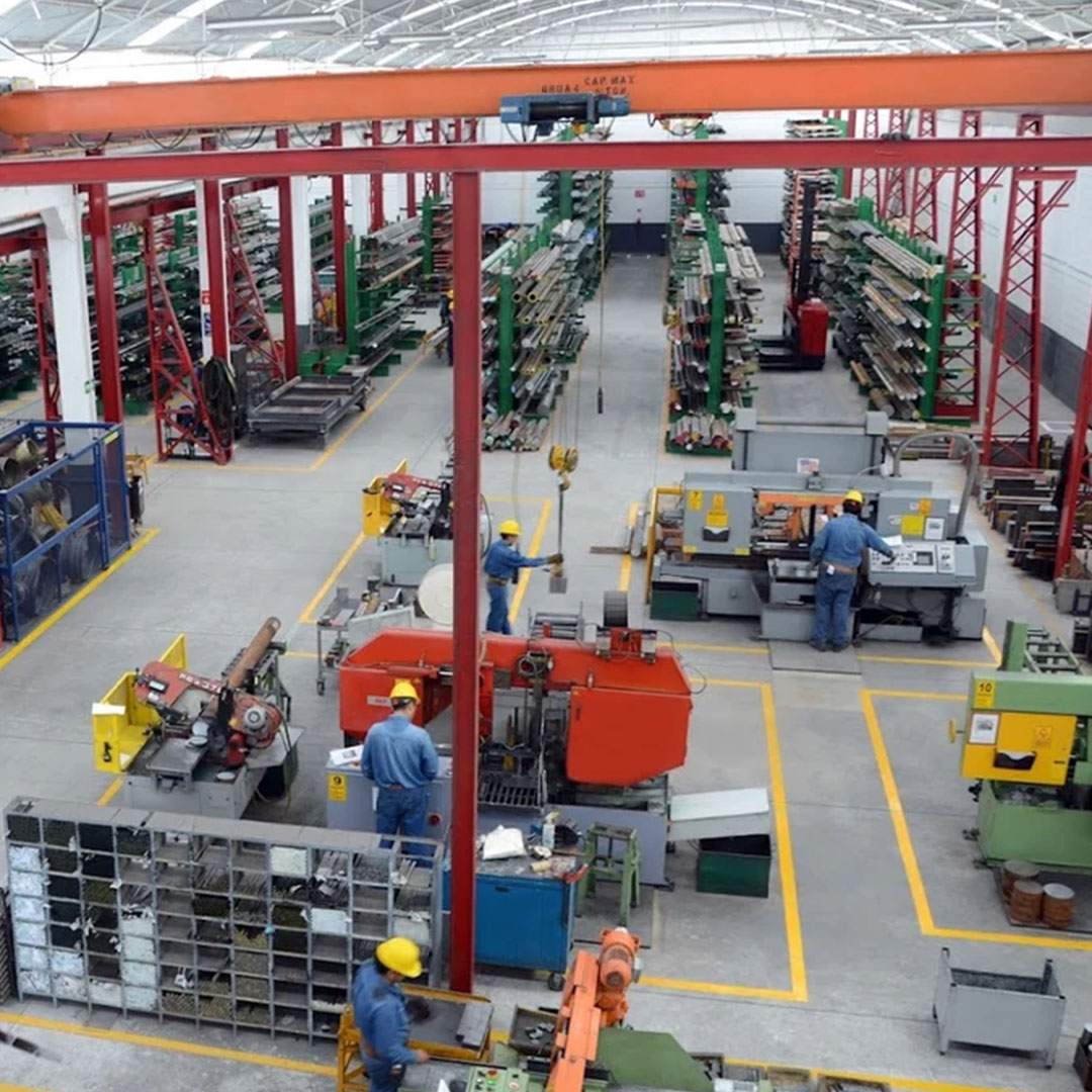 Vista aérea de las instalaciones de una fábrica de aceros, repleta de trabajadores que operan estratégicamente herramientas y maquinaria.